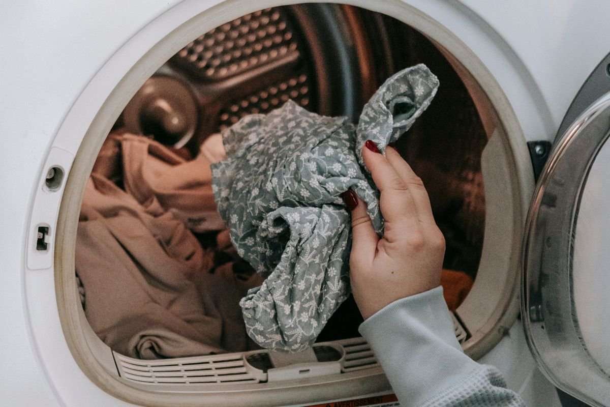 Una persona carga ropa en un lavarropas en su casa.