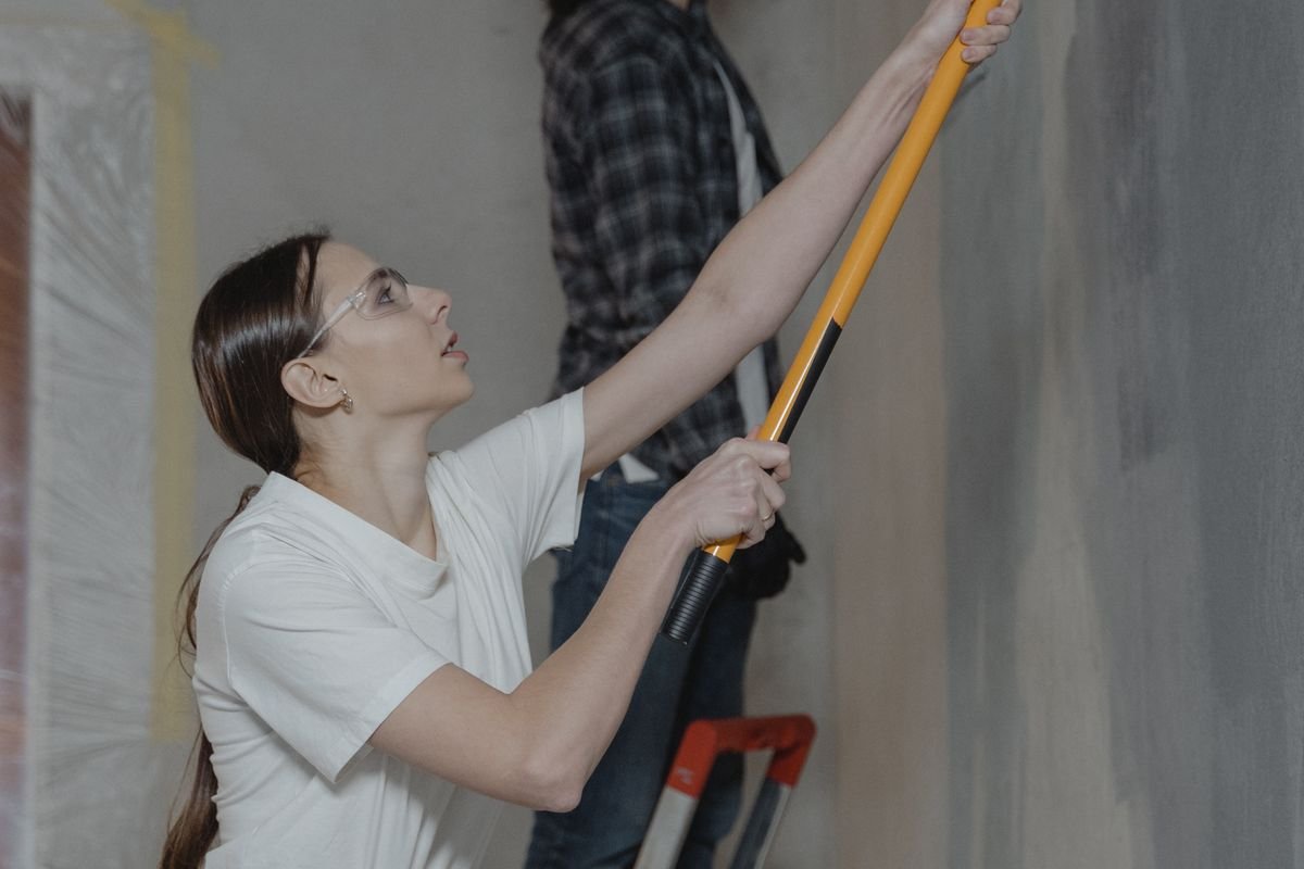 Una pareja pinta una pared como parte de una mejora del hogar.