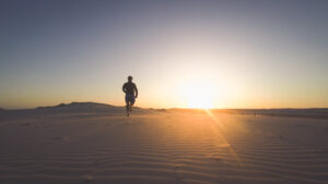 Back view silhouette of a runner man running along on the beach