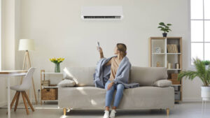 Woman enjoying cool fresh air in her living room with air conditioner on the wall